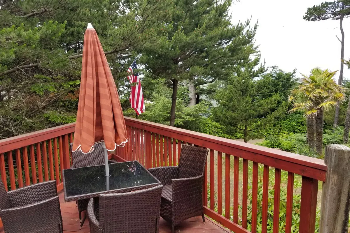An inviting outdoor dining area features a large table with umbrella, surrounded by trees and greenery. The space feels communal and comfortable, offering a place for relaxation after an active day outdoors.