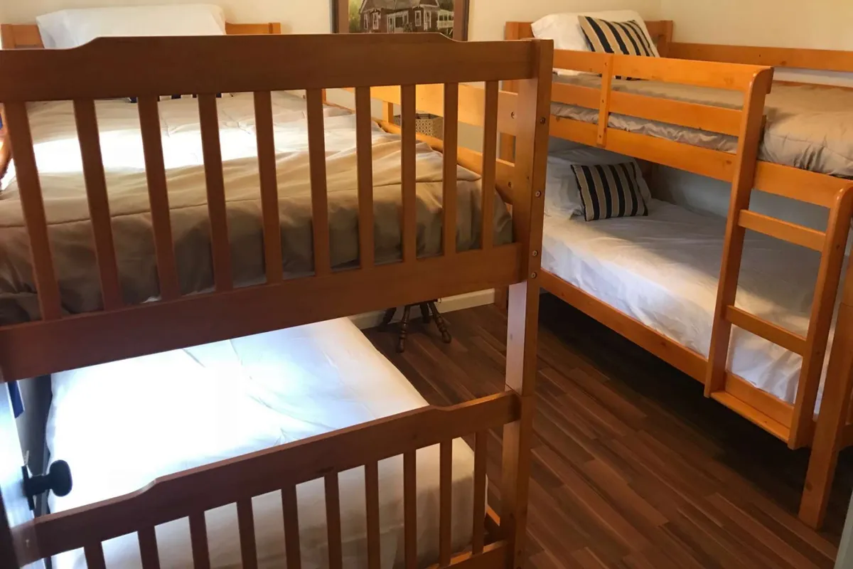 A cozy bedroom designed for younger guests, featuring two twin bunk beds with striped pillows and sturdy wood frames. The space feels playful yet comfortable, perfect for kids or teens sharing a room on vacation.